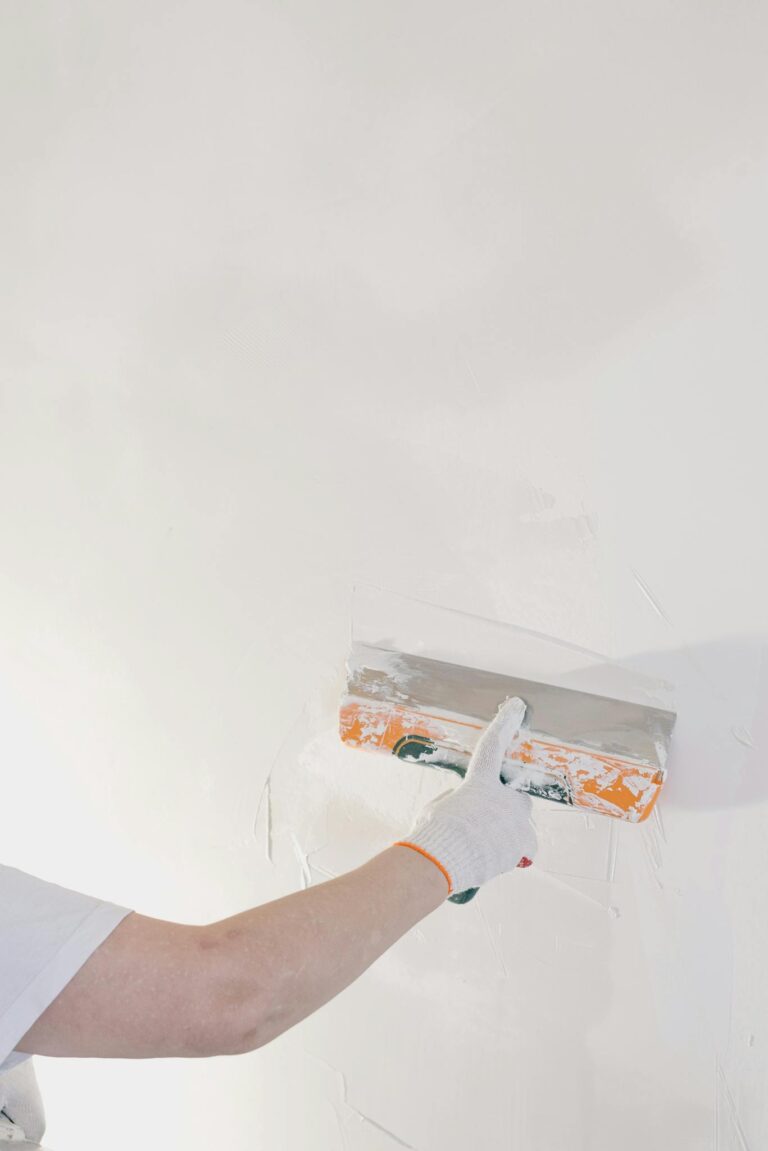Crop man plastering wall at home